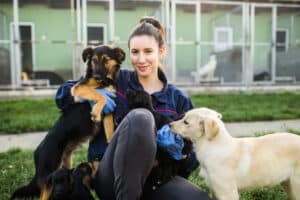 Woman sitting with two rescue dogs outside shelter